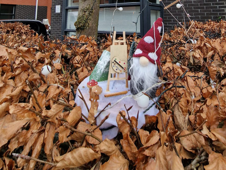 een tafereeltje met een kerstkabouter in een heg