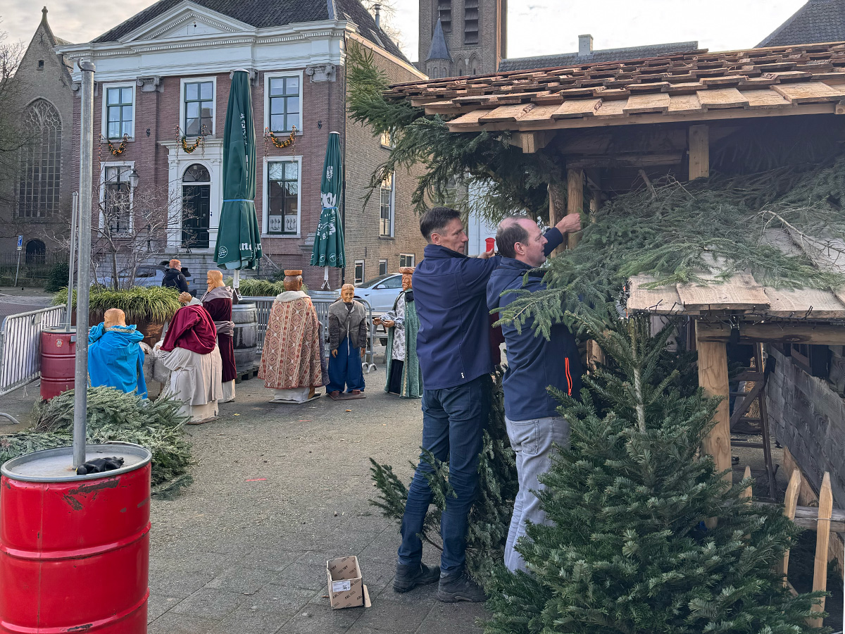 Ruud en Xander maken de lampjes vast. Op de achtergrond staan de beelden van de kerststal